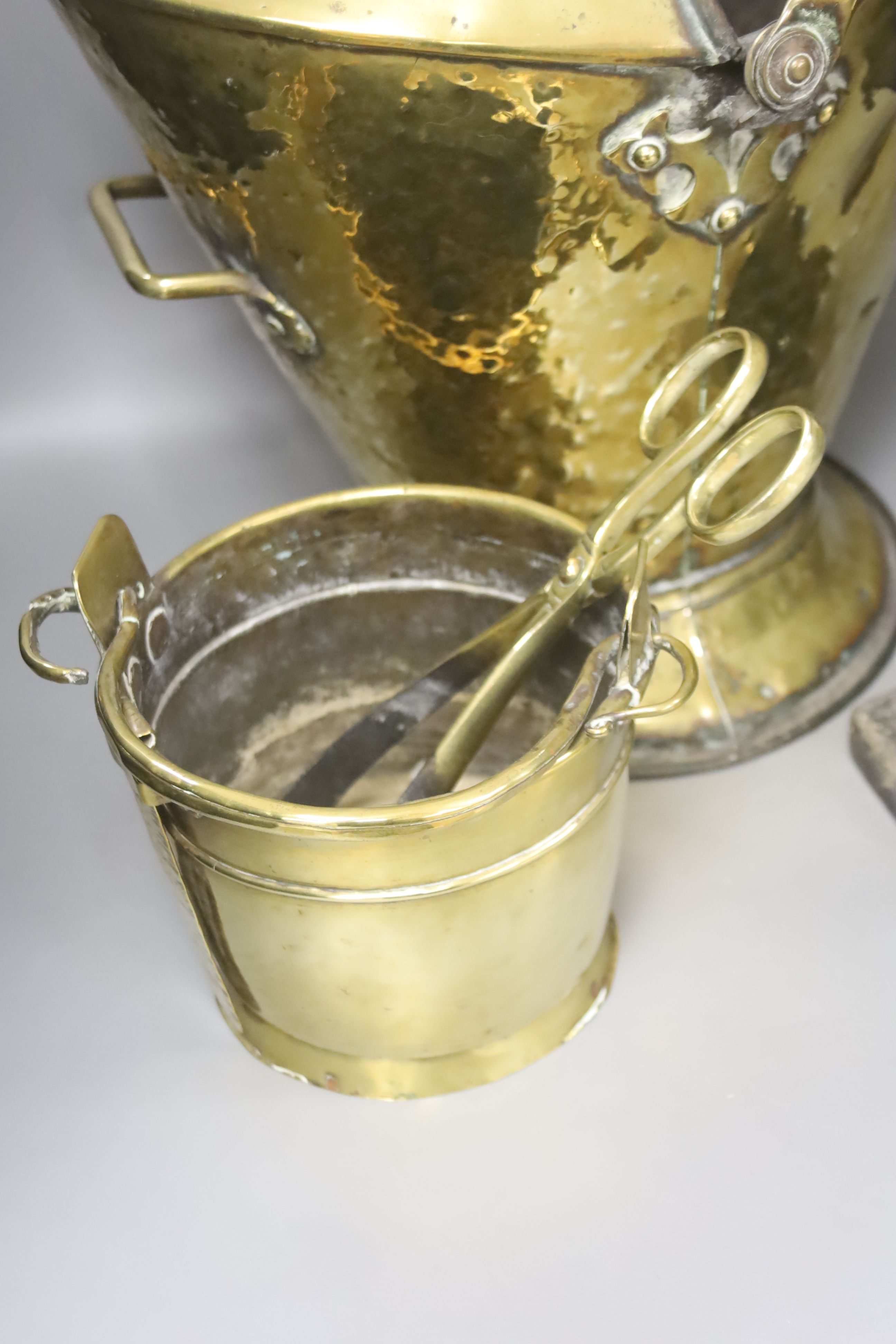 A brass coal bucket, a dolphin door porter, a scoop and a small pail, tallest 47cm